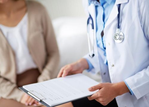 Doctor holding clipboard next to patient
