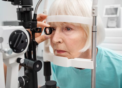 Senior woman eyesight test with binocular slit-lamp. Checking retina of a female eye close-up. Vision correction of elderly people
