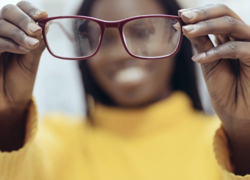 Woman holding up red eyeglasses